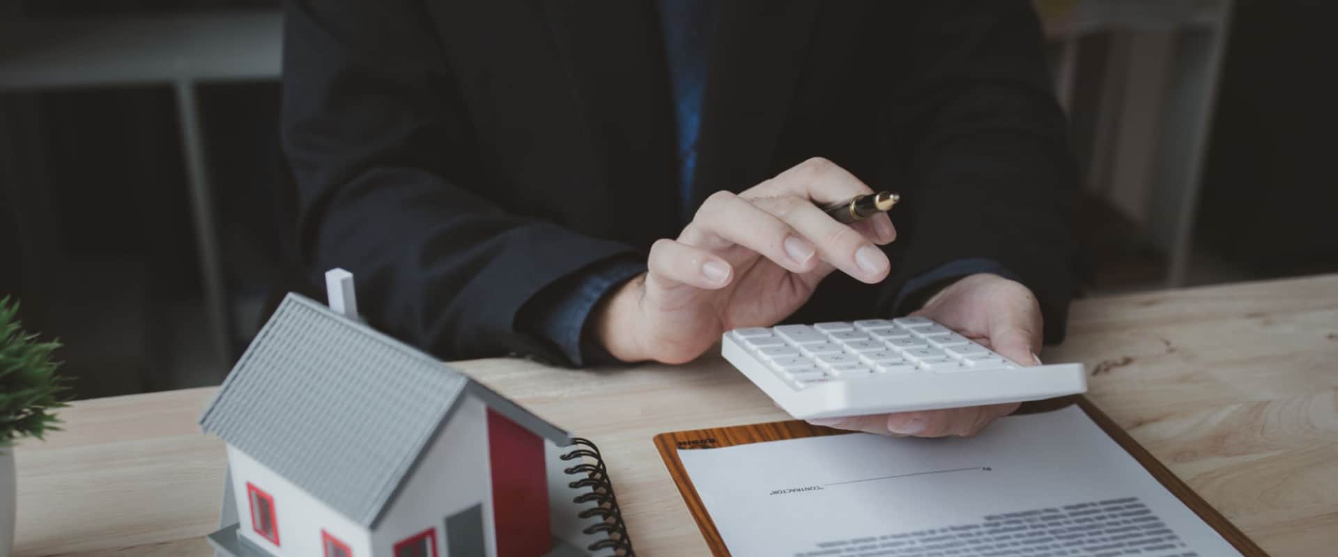 Девушка высчитывает на калькуляторе сумму погашения льготного кредита при продаже вторичной квартиры