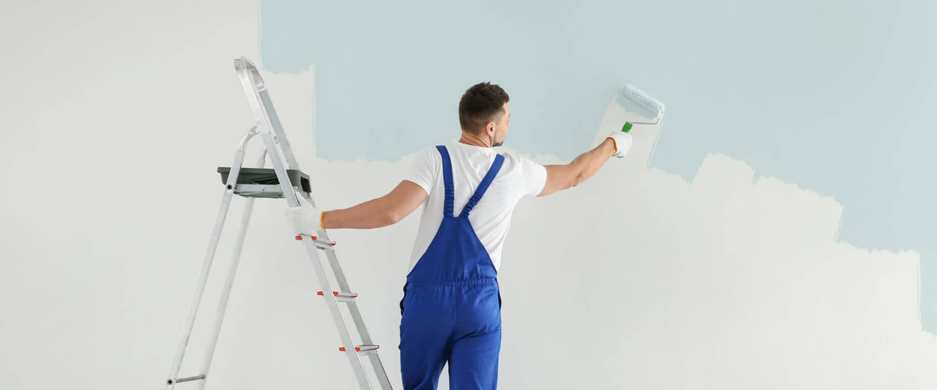 Человек красит стены, тем самым занимаясь предпродажной подготовкой вторичной квартиры