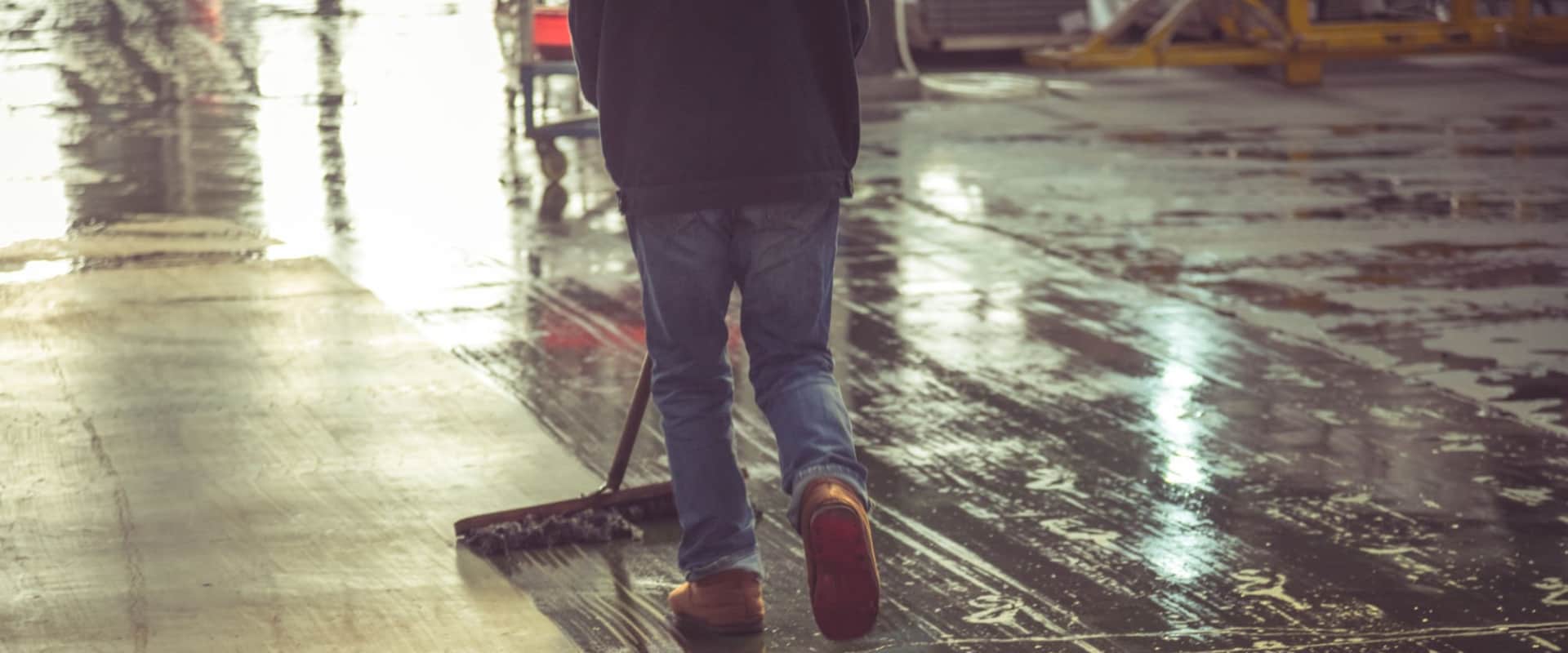 Человек моет пол и приводит в порядок складское помещение для сдачи в аренду