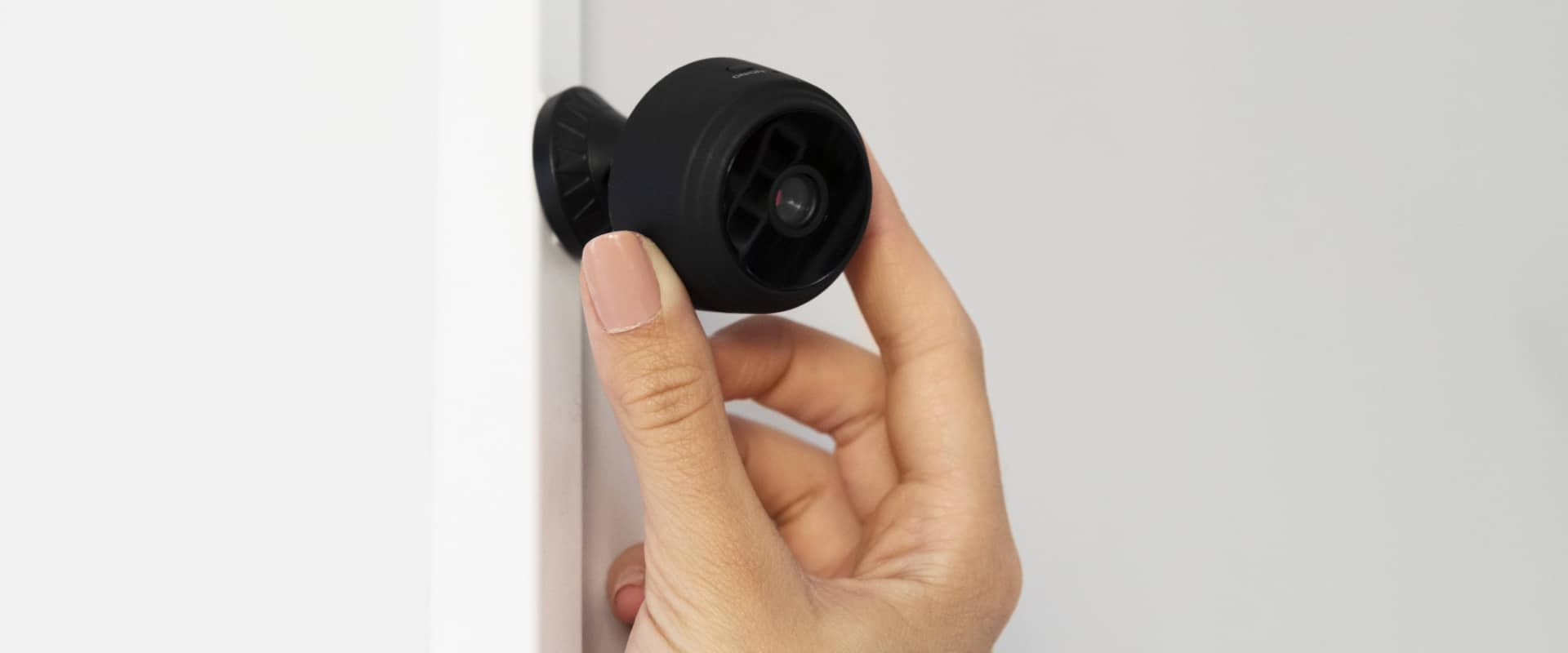 Девушка устанавливает камеру наблюдения в подъезде жилого многоквартирного дома